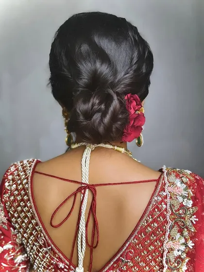 A classic bridal bun adorned with a single, vibrant red rose. This is a simple yet powerful statement, perfect for a bride who loves timeless romance.