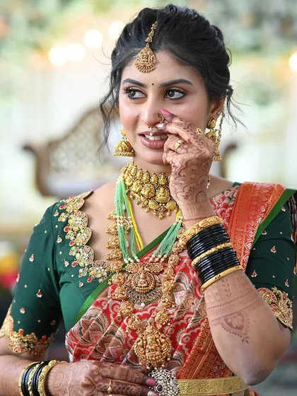 The joy on a client's face is my biggest reward. Here is a beautiful bride looking radiant in her custom-designed green blouse with delicate embroidery that perfectly complements her traditional red and gold wedding saree.
