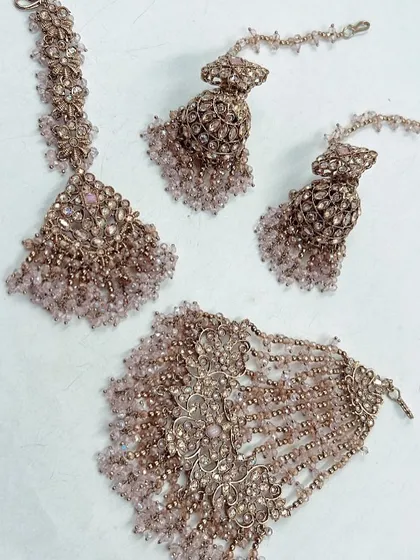 A delicate pastel pink beaded set, perfect for a Haldi or Mehendi ceremony. This rental set includes a maang tikka, hathphool, and earrings to complement your outfit.