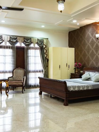 A spacious bedroom in the palace, featuring classic wooden furniture, a rich damask wallpapered accent wall, and elegant drapery, creating a cozy yet royal retreat.