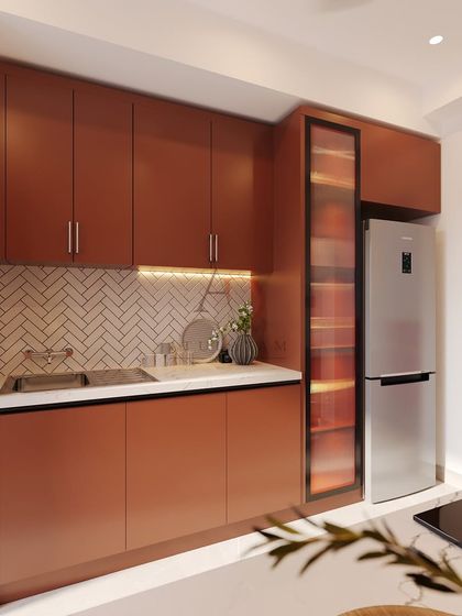 A compact kitchen or pantry space with warm, rust-toned cabinetry, a herringbone tile backsplash, and an integrated refrigerator.