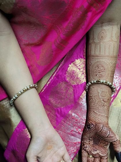 A beautiful bridal mehendi for Anushiya, set against her vibrant pink saree. The design features bold mandalas on the palm and detailed cuff work on the arms, showing how the henna complements the entire bridal look.