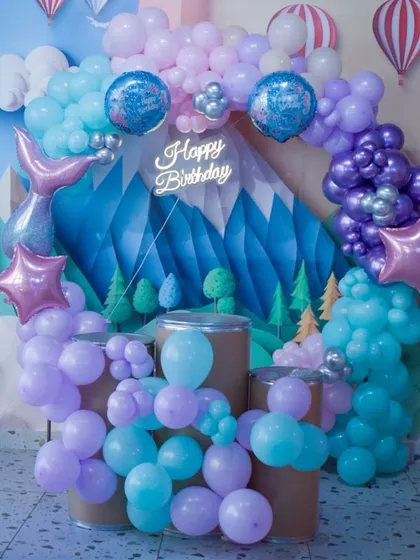 A dreamy mermaid-themed balloon setup in pastel purples and blues, with a neon "Happy Birthday" sign for a modern touch.