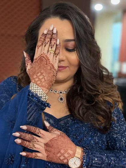Another angle of the eye-covering pose, showing the flawless makeup and beautiful henna details.