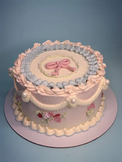 I'm obsessed with bringing back old-world charm. This vintage Lambeth cake features delicate pastel pink and blue ruffles, a sweet bow, and hand-piped floral details. It’s all about creating an elegant centerpiece that marks the beauty of an occasion.