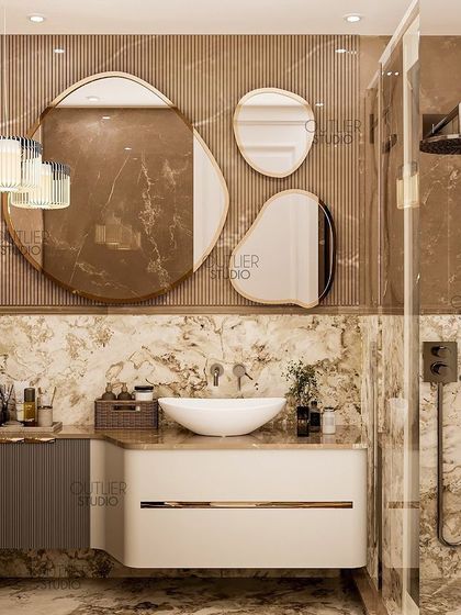 Flush with finesse. This bathroom design uses a rich brown marble, a custom vanity with a curved design, and a set of organic-shaped mirrors to create a warm, earthy, and luxurious space.