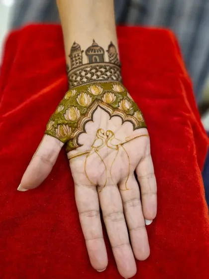 A unique Indo-Western design with two swans forming a heart shape. The wrist is adorned with a band of lotus flowers and a palace skyline.
