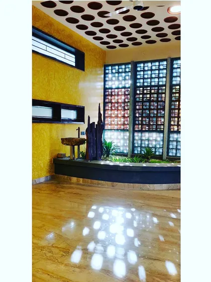 A corner garden comes to life as light streams through a perforated ceiling. The circular patterns are reflected on the polished floor, creating a playful "scoop scape" that merges solid form with ephemeral light.