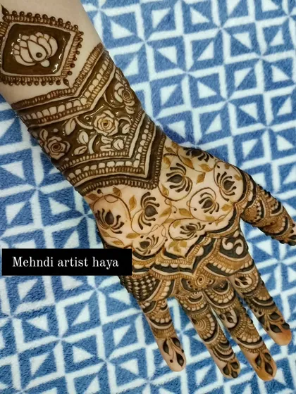 The completed bridal design, featuring a prominent lotus in a square frame on the forearm, surrounded by delicate floral vines.