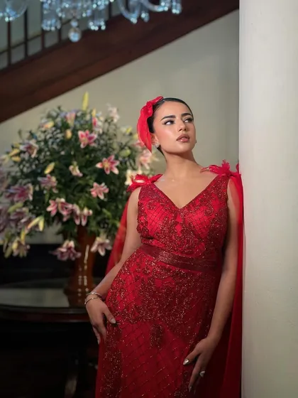 A full-length view of this incredible red gown. The makeup is designed to be as show-stopping as the dress itself.