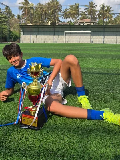 A relaxed, celebratory pose on the grass with the championship trophy.