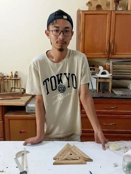 This student is exploring geometric forms, creating a triangular trivet or art piece using Kumiko techniques.