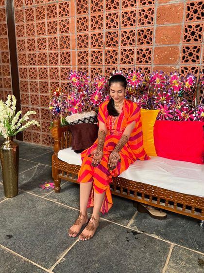 A serene shot of Rupa, seated and admiring her freshly applied mehendi on her hands and feet.