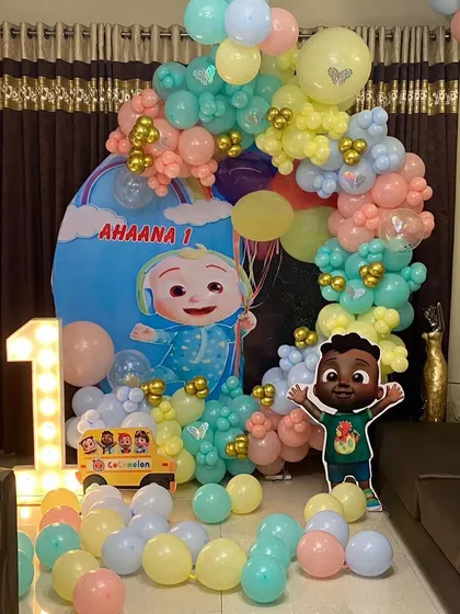 Another angle of the pastel Cocomelon first birthday setup. This view shows the arrangement of the character cutouts and the spread of loose balloons on the floor to create a playful environment.