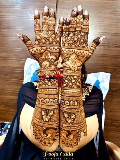 The back of the hands from a beautiful engagement mehendi session. This design features geometric grids, floral patterns, and peacock motifs for a full and balanced look.