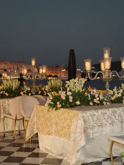 The guest seating for the ceremony is designed for both comfort and style. Here, elegant tables are set by the water at The Leela Palace Udaipur, offering a stunning view of the city palace.
