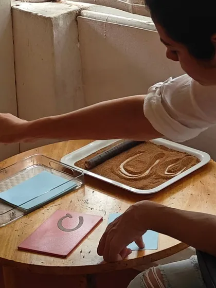 A parent experiences the simple, profound activity of writing in a sand tray. This tactile work helps you connect with the way your child learns through their senses, building empathy and insight into their development.