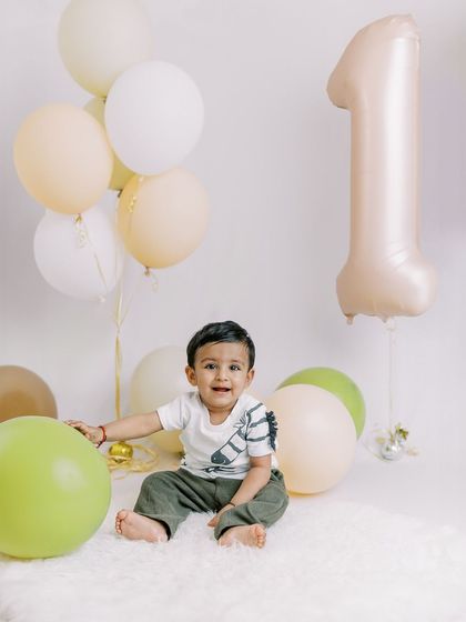 A happy one-year-old surrounded by balloons. The simple joy on his face is what makes these sessions so special.