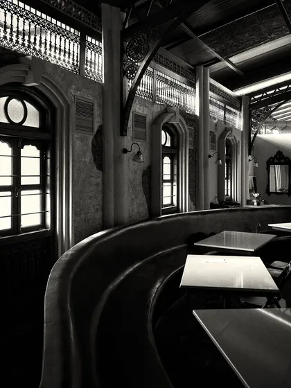 A long, curved banquette provides seating along the wall, punctuated by arched windows that bring in natural light.