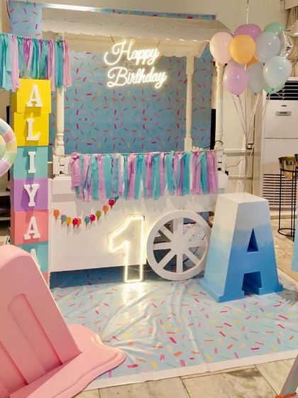 This candy-themed first birthday for Aliya was all about sweet pastels. We used a candy cart as the main backdrop, complemented by a neon 'Happy Birthday' sign, a light-up number '1', and large custom-painted name blocks.