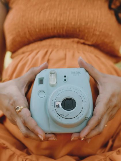 Making memories to show you one day. Using a polaroid camera as a prop is a fun, retro touch that symbolizes capturing all the precious moments to come.