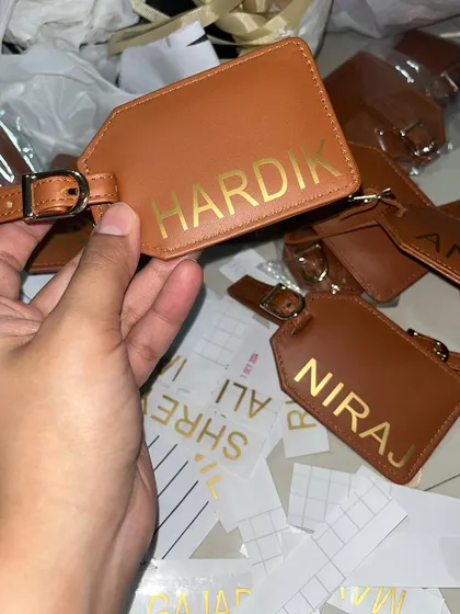 The process of personalizing leather luggage tags with gold foil names. This behind-the-scenes shot shows the craftsmanship involved in our custom gifts.