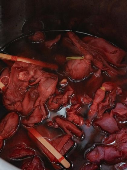 Fabric bundles simmering in a natural dye bath. This is where the colour transfer happens, infusing the cloth with beautiful, earthy red tones.
