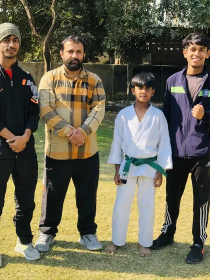 This young green belt has a bright future. He is standing with the senior coaches who guide him.