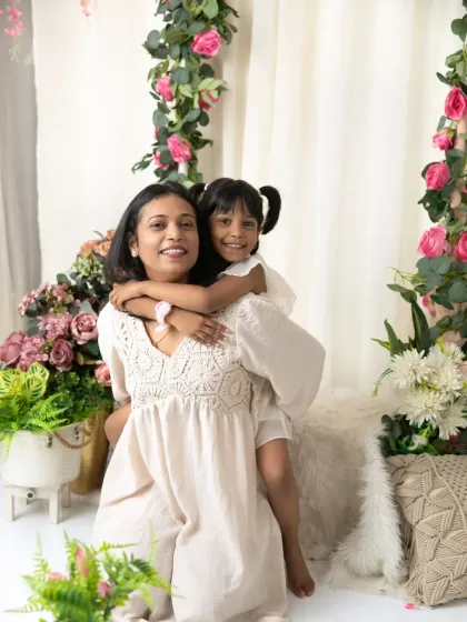 A playful piggyback ride for a daughter on her mom's back, both sharing a laugh in our floral studio setup.