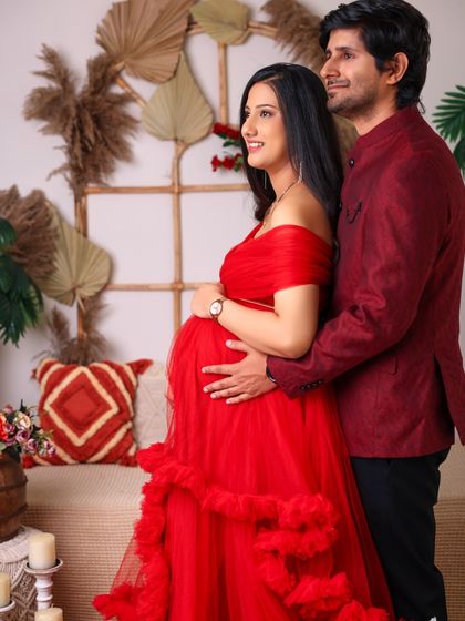 A tender moment between partners. The father-to-be gently holds her from behind, both looking forward to their new chapter in our warm, boho-themed studio.