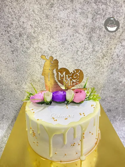 A classic Mr. & Mrs. wedding cake. The white drip and floral toppers create a simple, elegant look for the special day.