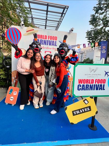 A group of friends posing at the World Food Carnival photo-op. Our events are designed to create fun, shareable moments with unique backdrops and mascots.