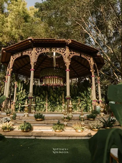 The Bandstand, decorated with lush greenery and a grand chandelier, transformed into a breathtaking mandap for a nature-inspired wedding.