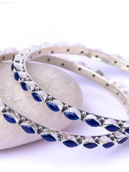 A pair of elegant silver bangles with marquise-shaped blue enamel work. These can be stacked or worn individually for a pop of color.