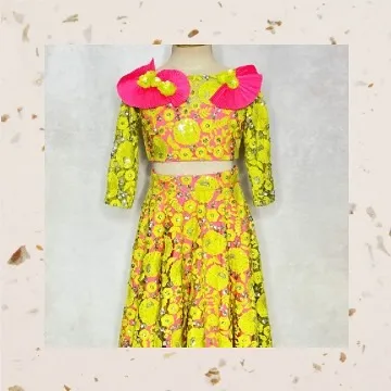 For the girl who loves to stand out, this fluorescent lehenga is pure fun. It features neon yellow embroidered net over a bright pink base, with quirky pleated flowers on the shoulders.