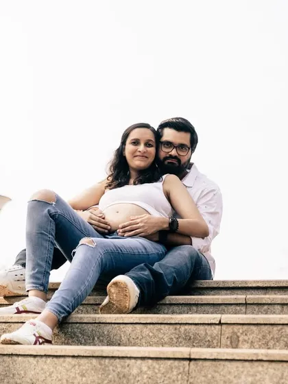 A casual, urban maternity shoot can feel so modern and real. This couple, dressed in simple jeans and white tops, shares a relaxed and confident moment together on a set of city steps.