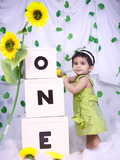 Marking a first birthday with a sunflower theme. This little girl is standing proudly next to 'ONE' blocks.