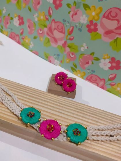 This boho-style choker is made with embroidered flower motifs and a braided cord. It's a delicate yet eye-catching piece that comes with matching stud earrings.
