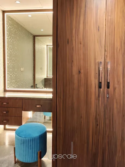 This dressing room combines the warmth of natural wood with the richness of Grigio Italian marble flooring. We focused on creating a functional yet luxurious personal space, using an illuminated mirror and a pop of color with the teal stool to add character and visual interest.