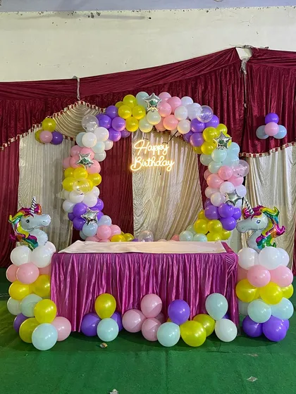 I create magical themed parties for kids, and the Unicorn theme is a favorite. This setup includes a full circular balloon arch in rainbow pastels, a glowing neon sign, and two unicorn-topped balloon pillars to frame the cake table.