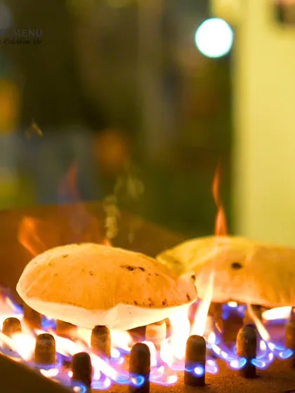 Roti being cooked over an open flame grill, puffing up perfectly. This showcases our commitment to serving fresh, hot Indian breads at events.