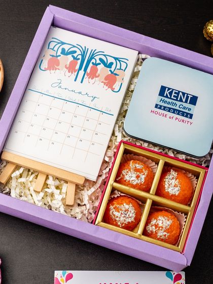 A corporate Diwali hamper featuring a custom-branded box from Kent, a desk calendar, and traditional Indian sweets. This is a great example of how I can incorporate your branding into a festive gift.