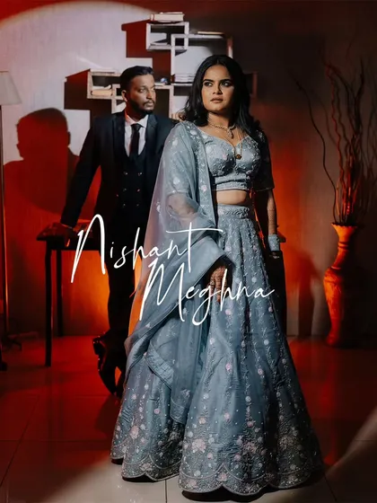 A stylish, full-length portrait of the couple at their reception, with dramatic lighting creating a spotlight effect.