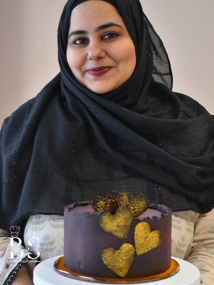 A beautiful ganache cake adorned with golden-dusted hearts, showcasing a blend of smooth icing and decorative texture work.