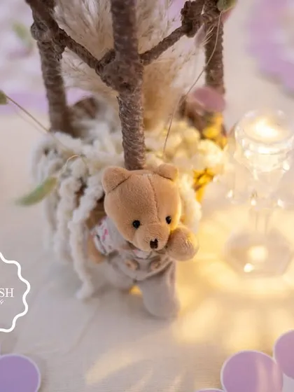 A tiny teddy bear peeks out from a hot air balloon centerpiece, a charming and whimsical detail from the "We Can Bearly Wait" baby shower.