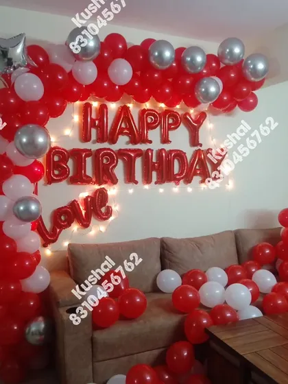 A red, white, and silver balloon arch over a sofa for a birthday celebration at home.