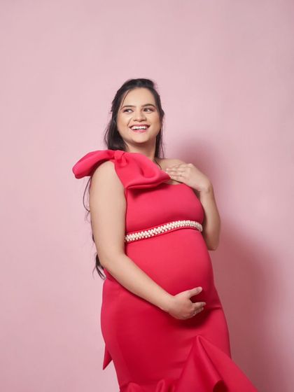 A joyful shot of our Gabriel gown. The one-shoulder design with a large bow detail is a fun and fashionable choice for a maternity shoot.