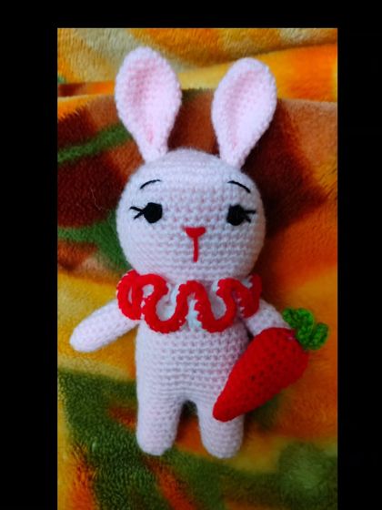 This cute handmade bunny is holding a carrot. It is a lovely toy for Easter or for any child who loves rabbits.