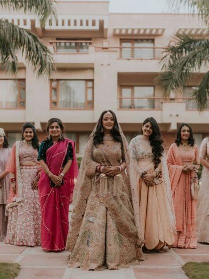 A lovely group portrait of the bride with her bridesmaids and family, all dressed in beautiful coordinated outfits.