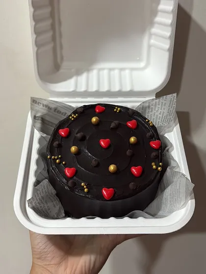 A decadent chocolate bento cake decorated with red hearts and golden sprinkles. This mini cake is perfect for a rich, chocolatey treat.